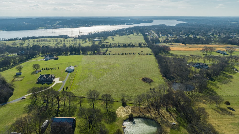 uma vista aérea de um grande campo com um lago ao fundo