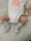 A baby wearing a white onesie with a peach design and the words 'PEACHY KEEN' written on it. The baby has gray socks with red text that reads 'MY FIRST XMAS'. A knitted teddy bear rattle is next to the baby, resting on a patterned surface.