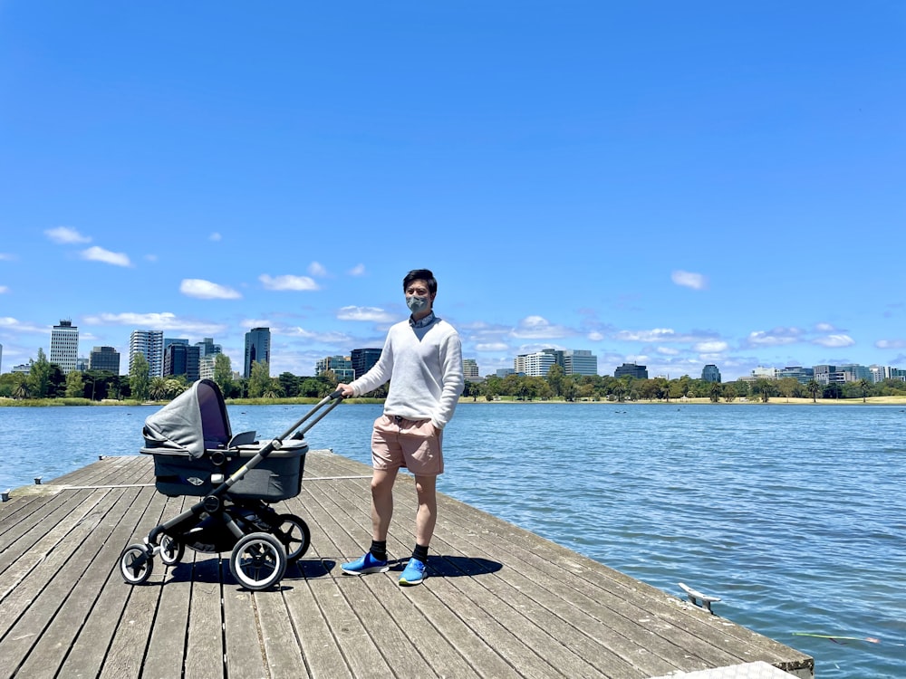 a man standing on a pier next to a baby carriage