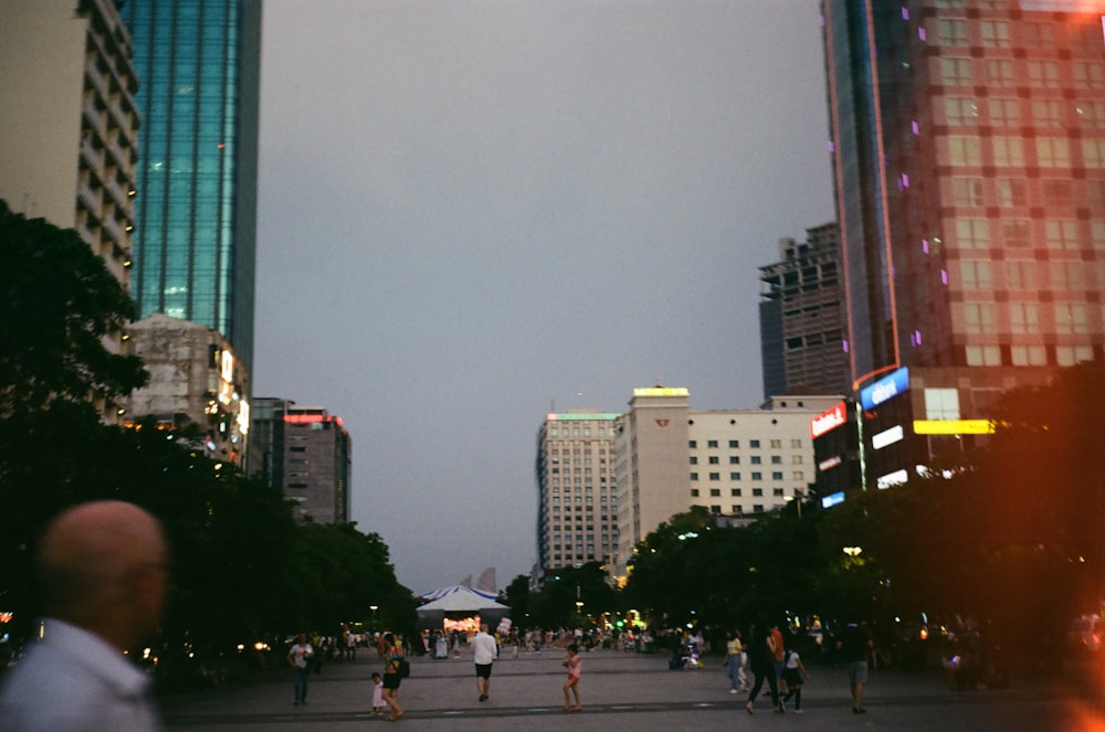 a group of people walking down a street next to tall buildings