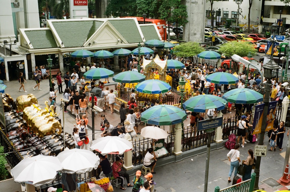 a crowd of people standing around tables with umbrellas