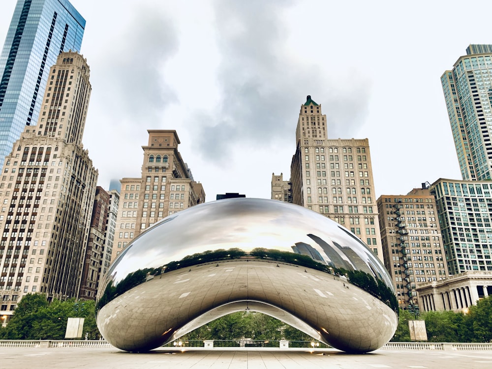 a large metal object in front of a cityscape