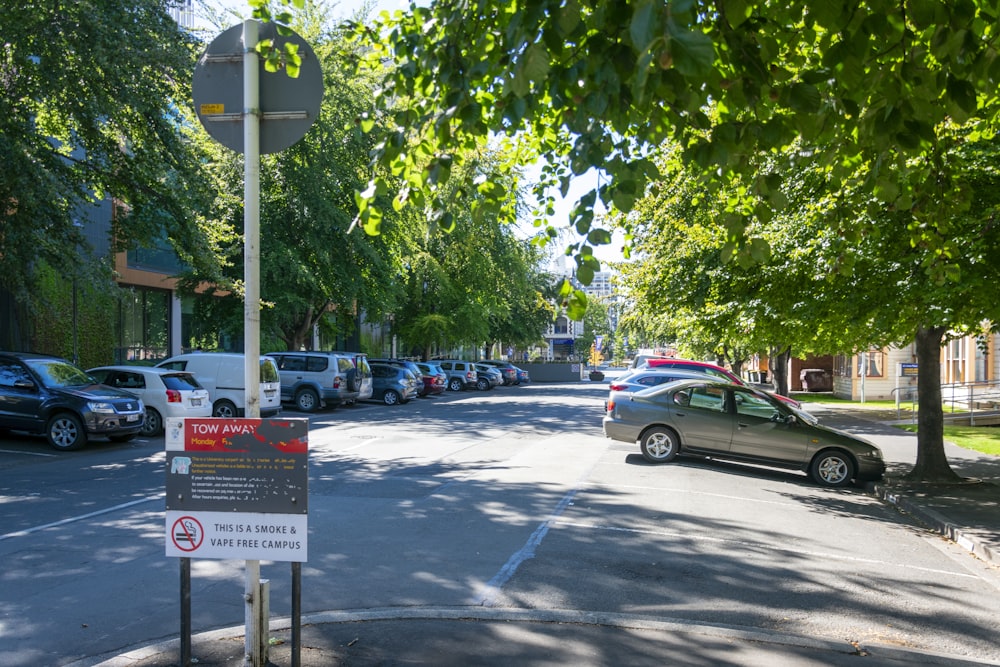 a street filled with lots of parked cars next to trees