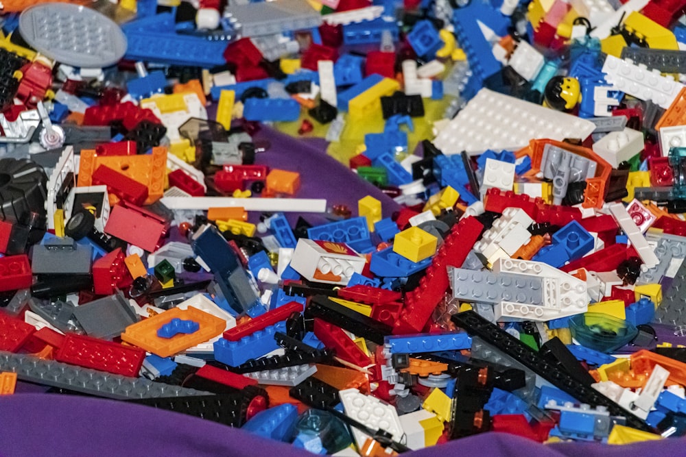 a pile of assorted legos sitting on top of a purple blanket