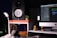 A well-organized workspace featuring an audio studio setup including a large speaker, a modern desktop computer displaying audio editing software, a pair of headphones resting on a stand, and a small potted plant for decor. The setup is illuminated by a sleek desk lamp, creating a warm, inviting atmosphere. Decorative owl figures also add a touch of personality to the space.