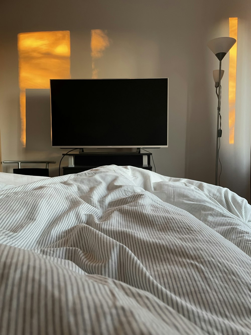 a bed with a white comforter and a flat screen tv