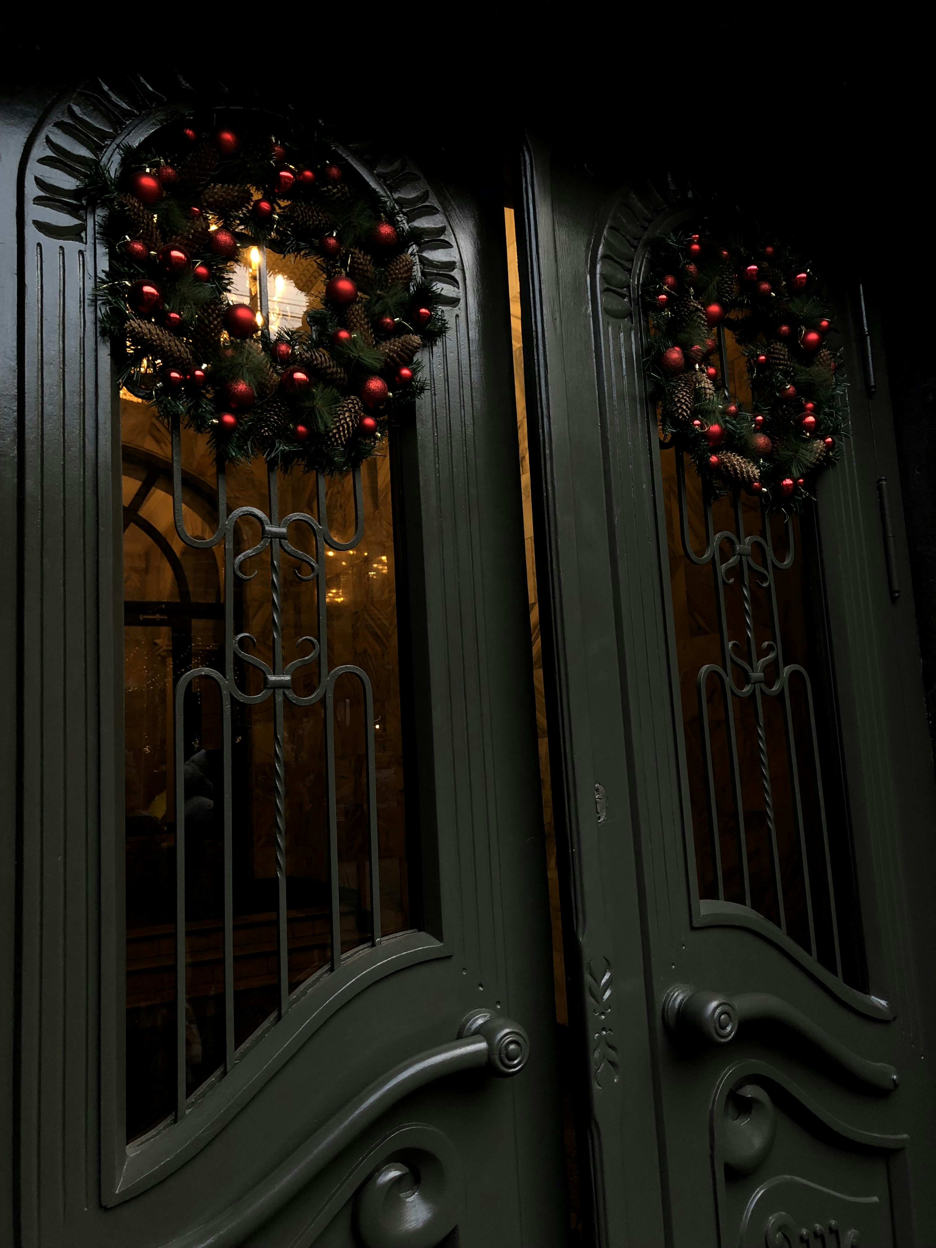 a pair of double doors decorated with christmas wreaths