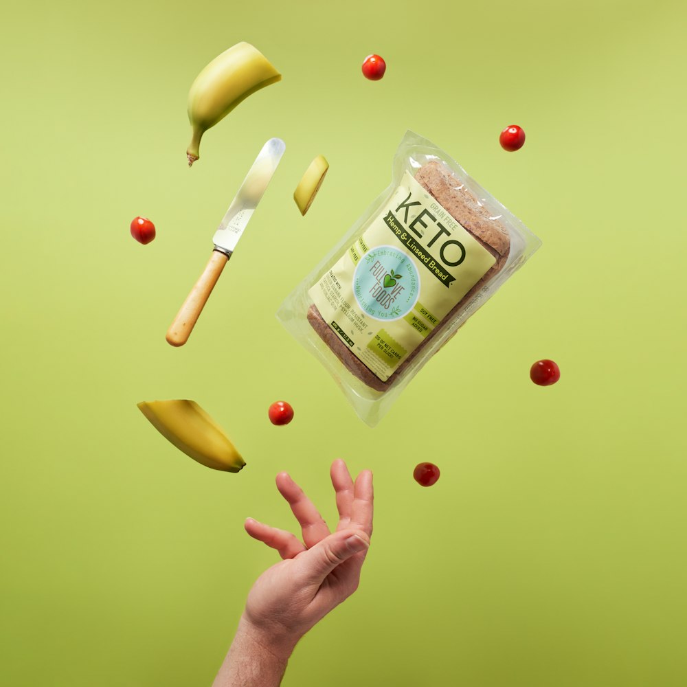 a hand reaching for a bag of food on a green background