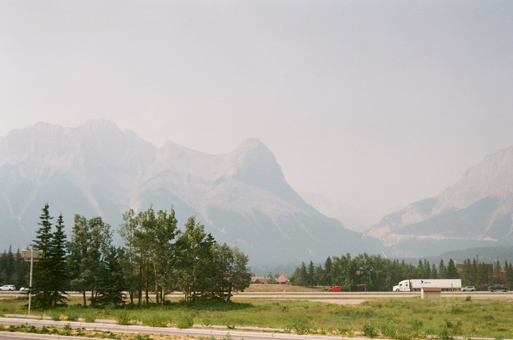 a truck driving down a road in front of a mountain range