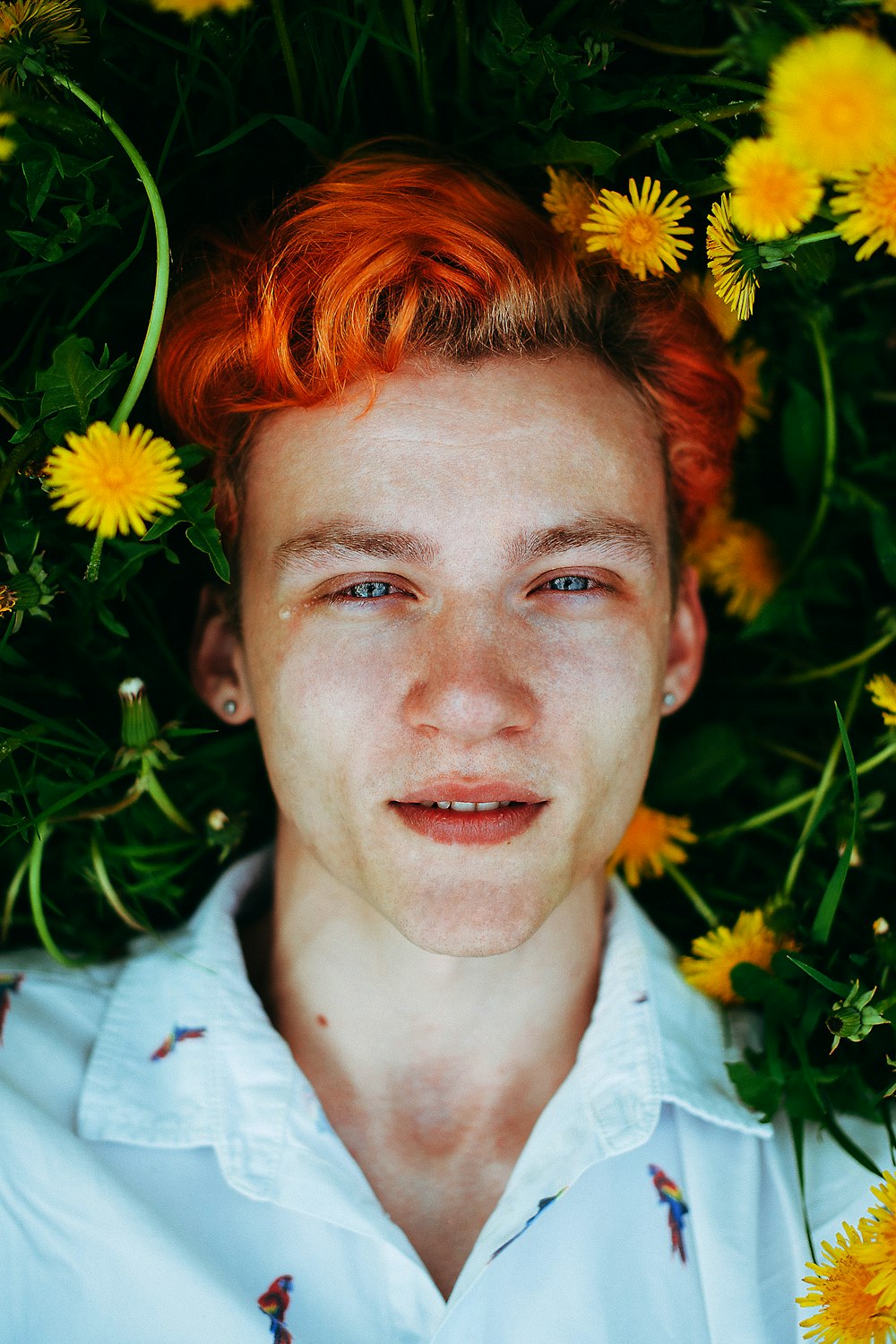 a man with red hair standing in a field of flowers