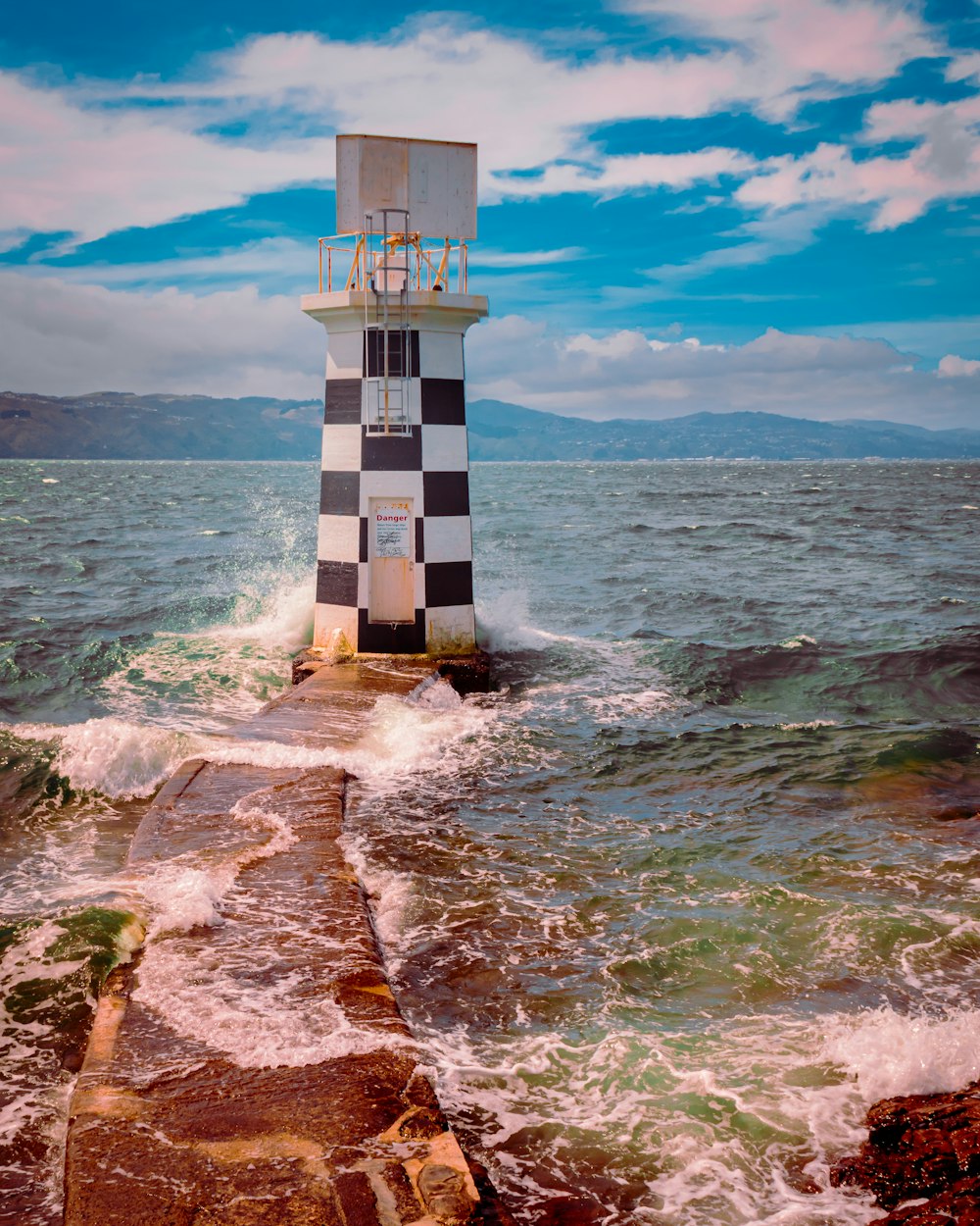 a black and white lighthouse sitting on top of a rocky shore