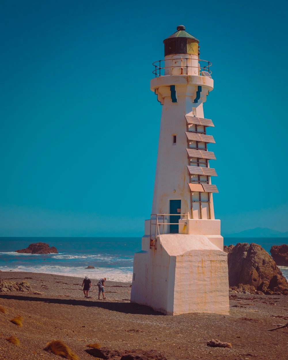 a tall white lighthouse sitting on top of a sandy beach