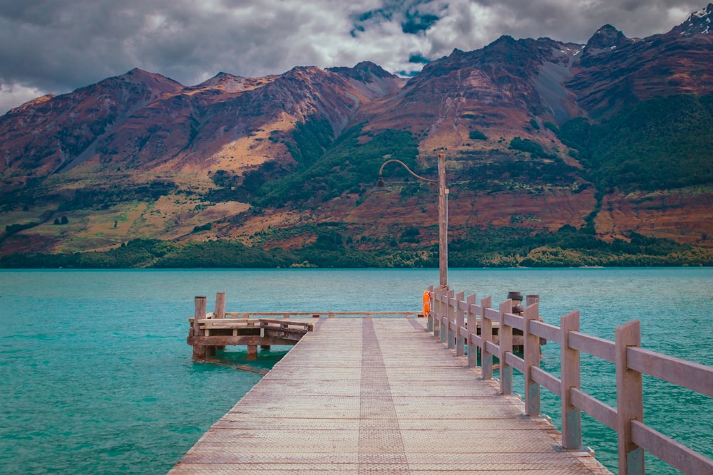a wooden dock with mountains in the background