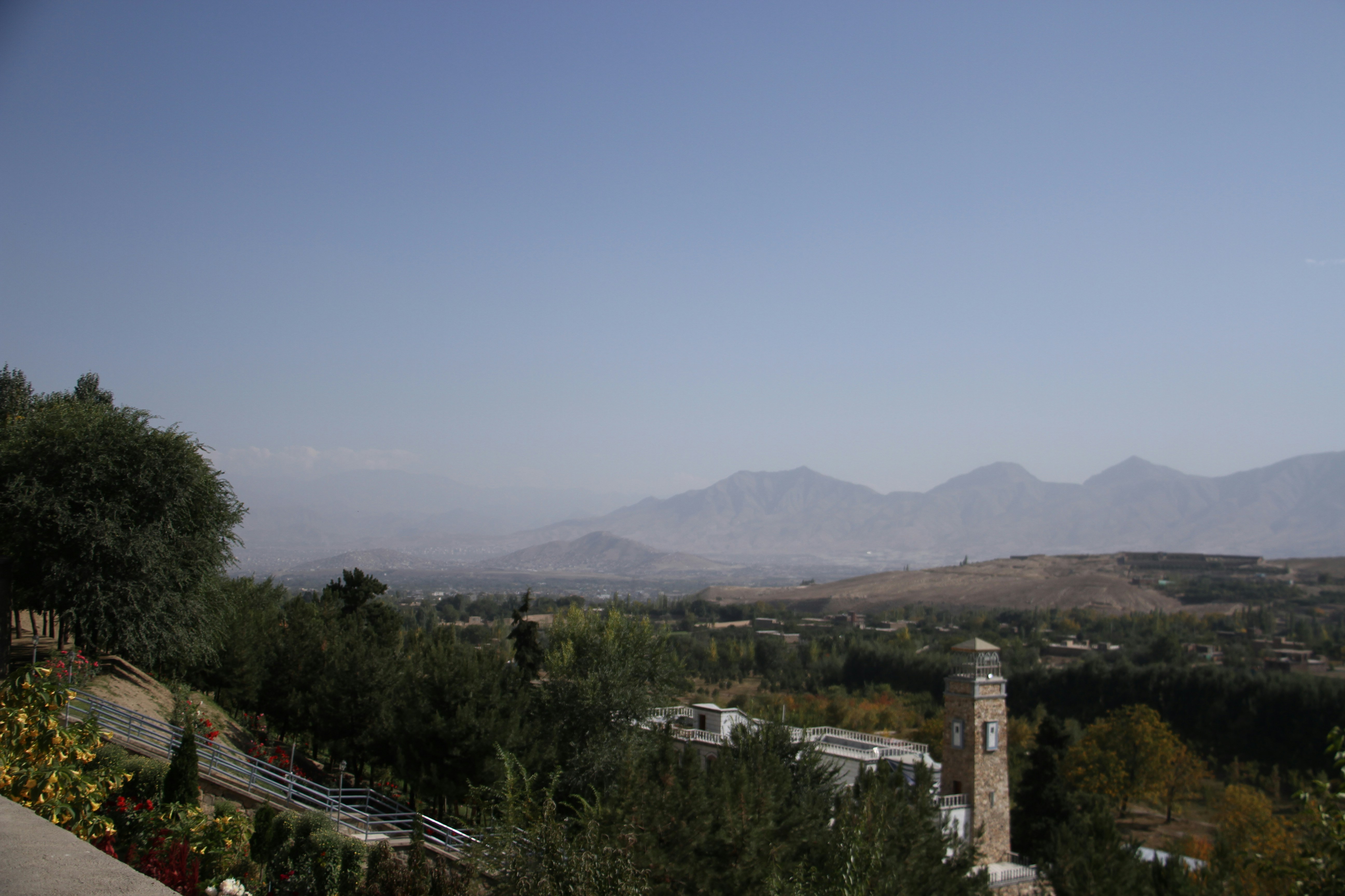 a view of a mountain range with a clock tower in the foreground, Paghman Garden Place 