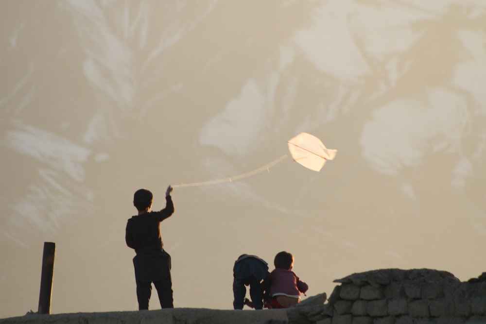 a man flying a kite on top of a mountain