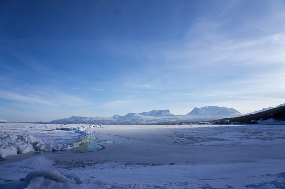 a large expanse of snow with mountains in the background