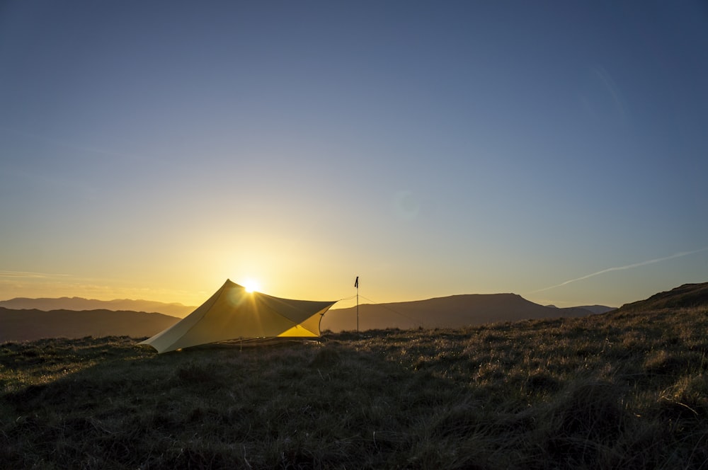 a yellow tent sitting on top of a lush green field