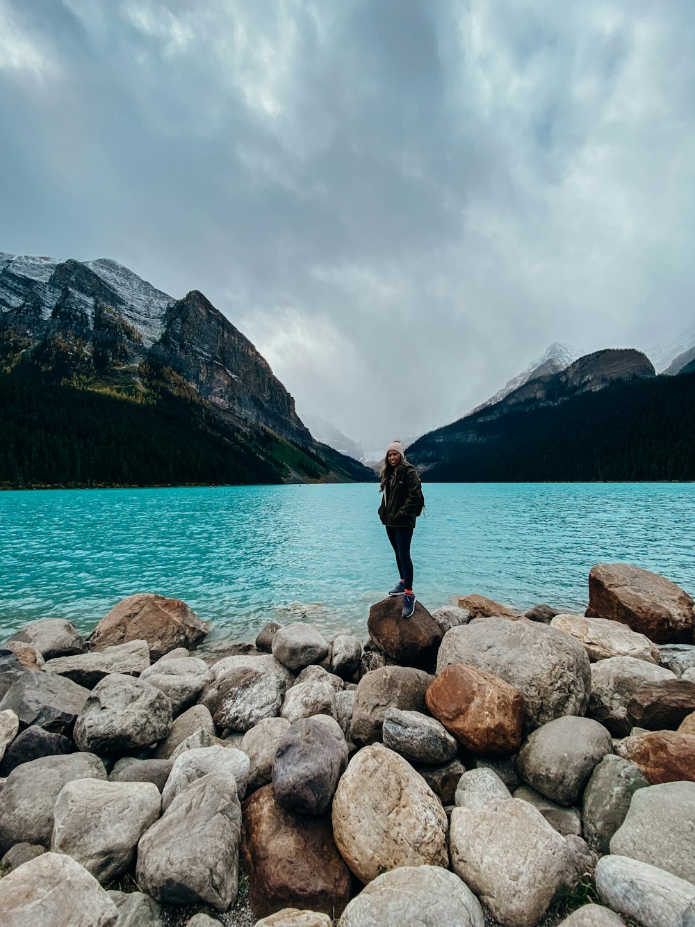 a person standing on rocks near a body of water