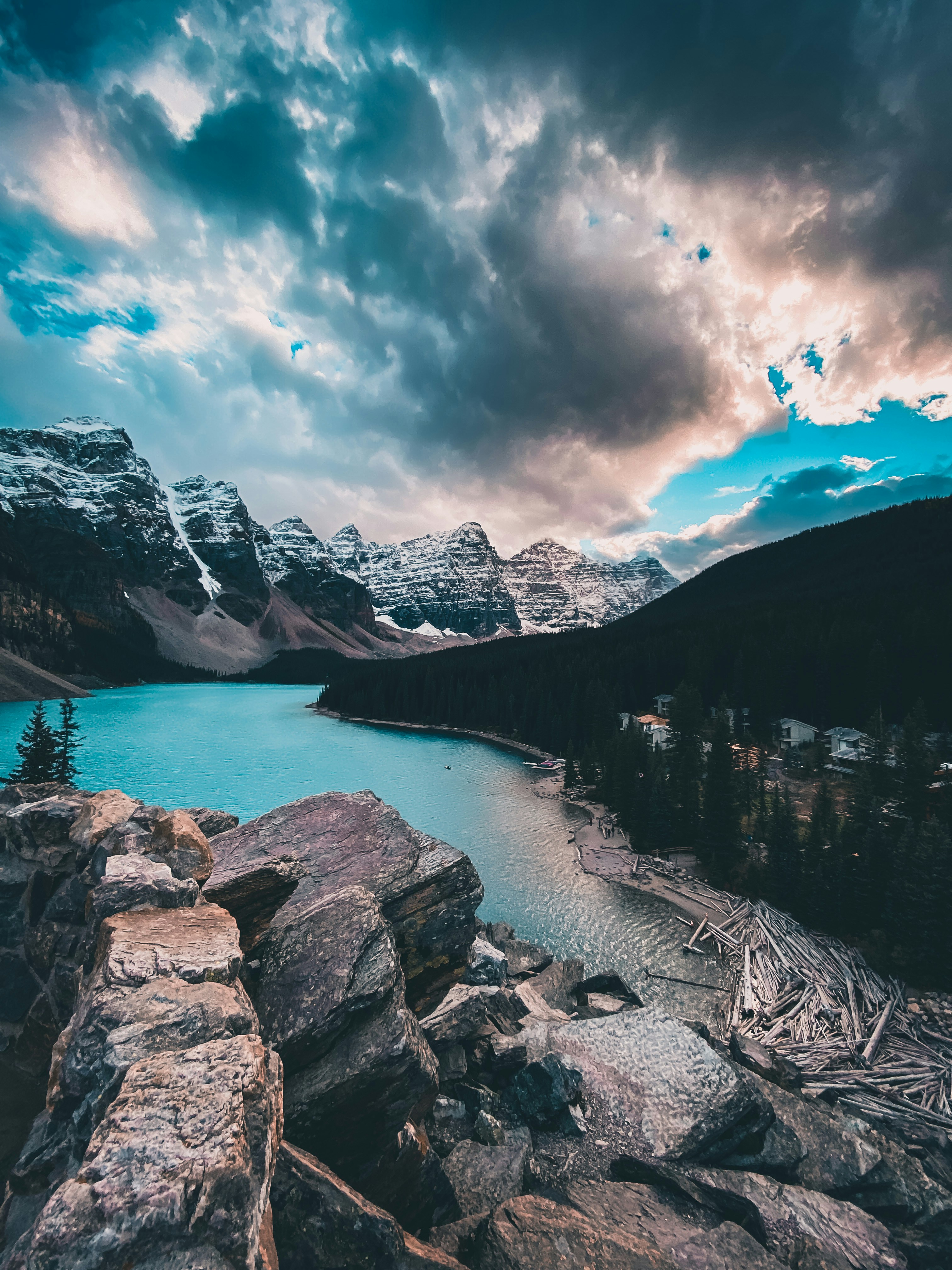 a lake surrounded by mountains under a cloudy sky