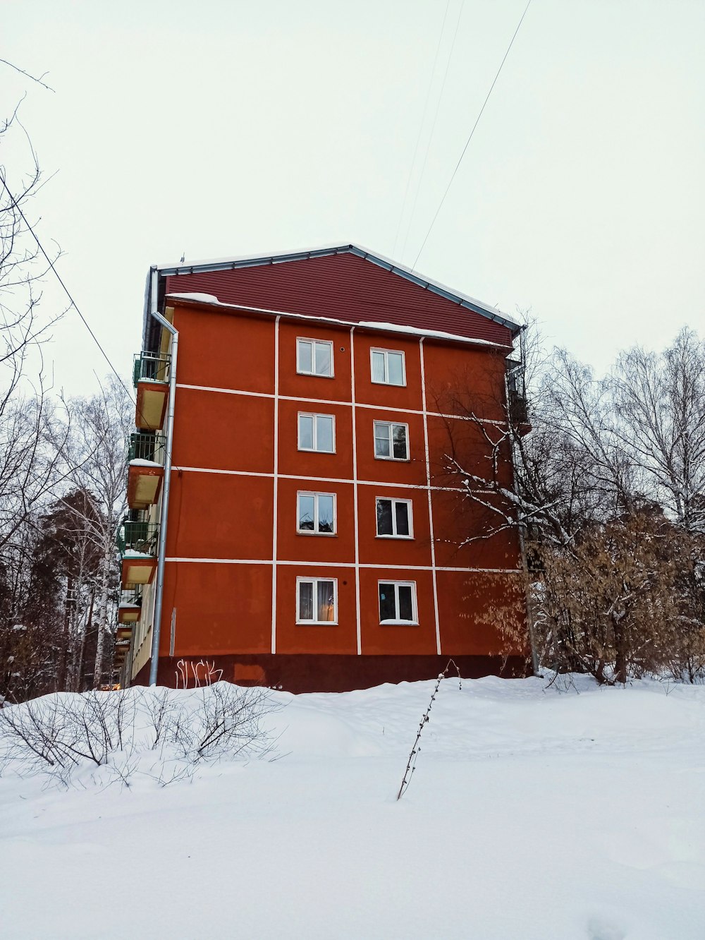 a tall red building sitting next to a snow covered forest