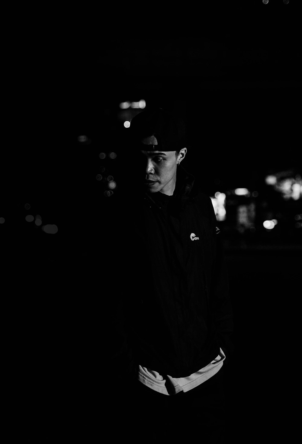 a man standing in the dark with a baseball cap on