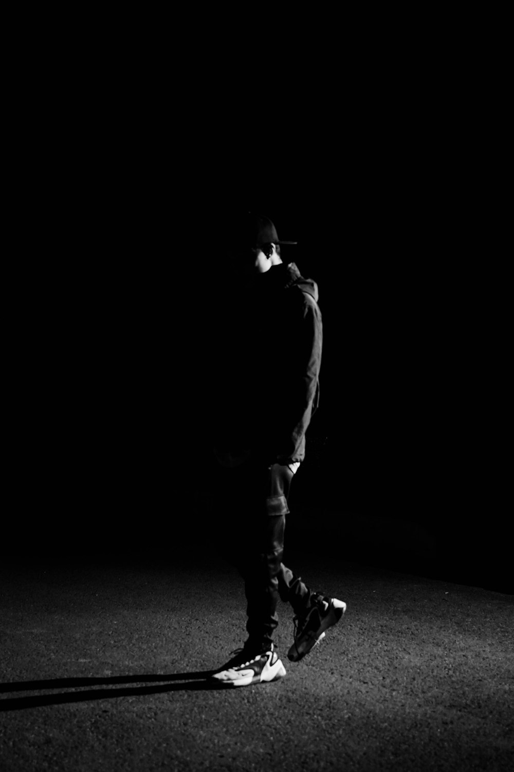 a man standing in the dark with a skateboard