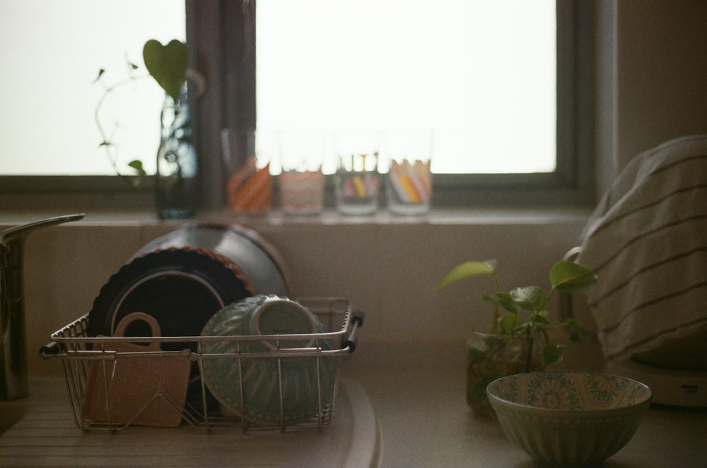 a kitchen counter with dishes in a basket next to a window
