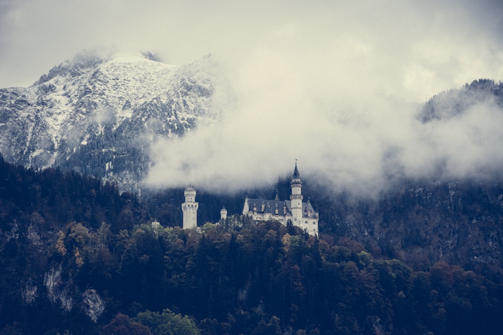 a castle in the middle of a mountain surrounded by clouds