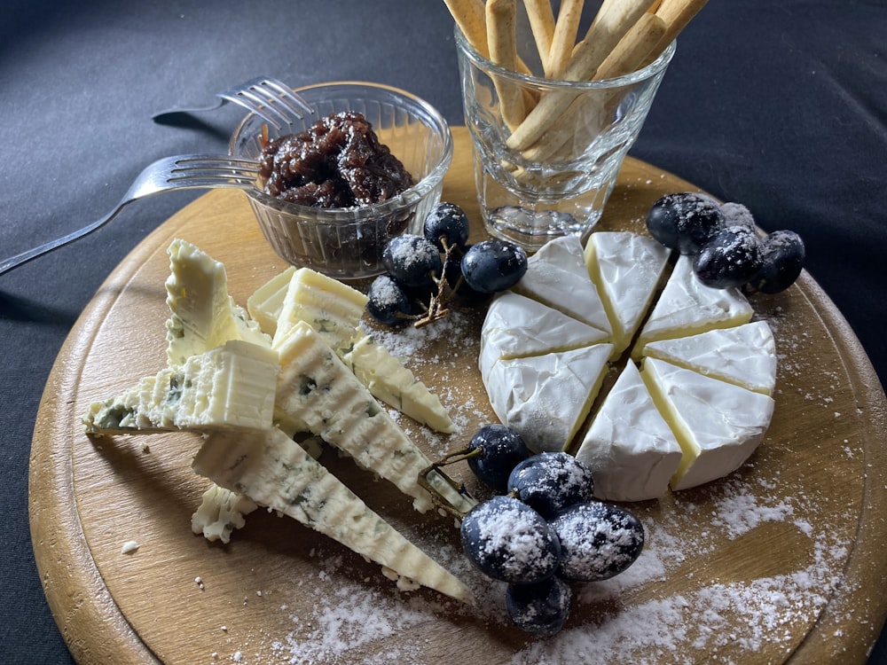 a wooden plate topped with different types of cheese