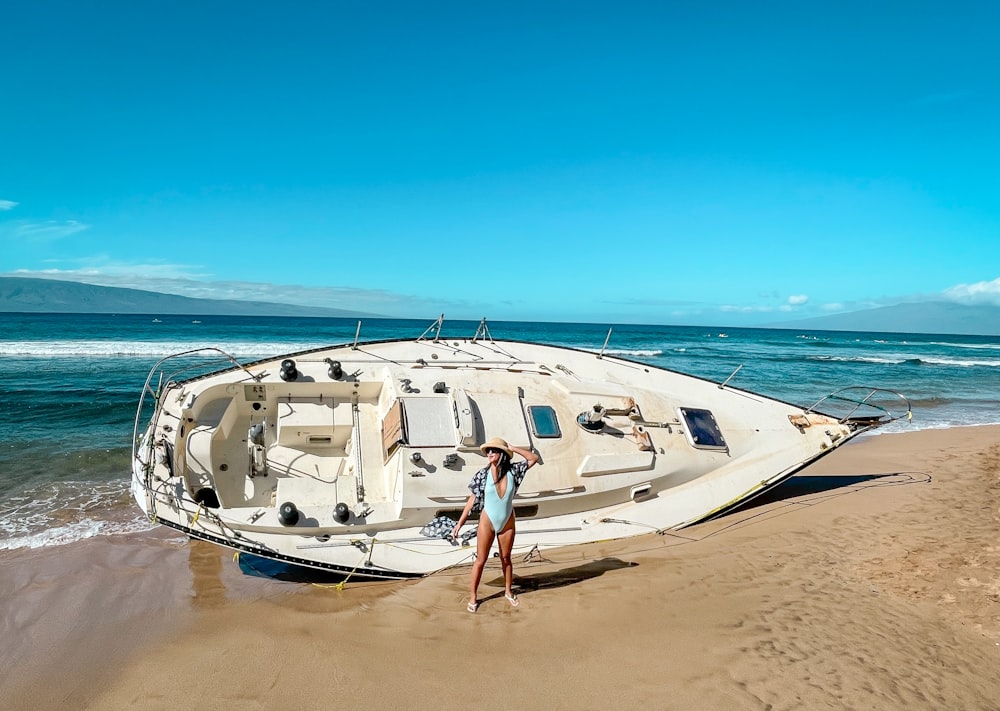 a couple of people standing next to a boat on a beach