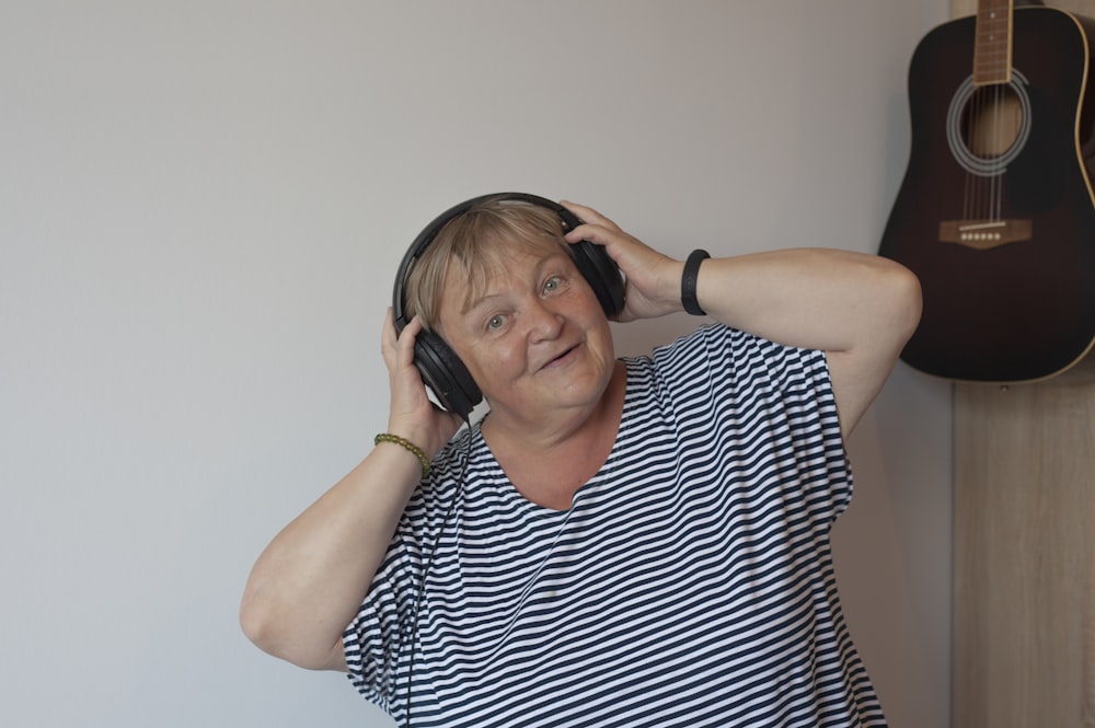 a woman with headphones and a guitar in the background