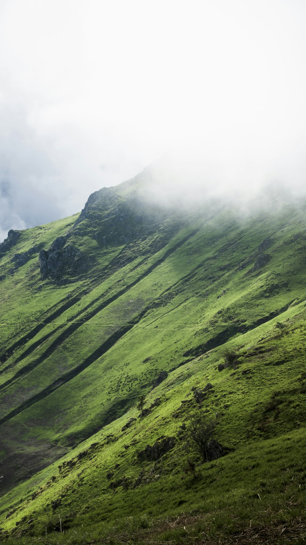 a grassy hill with a few clouds in the sky