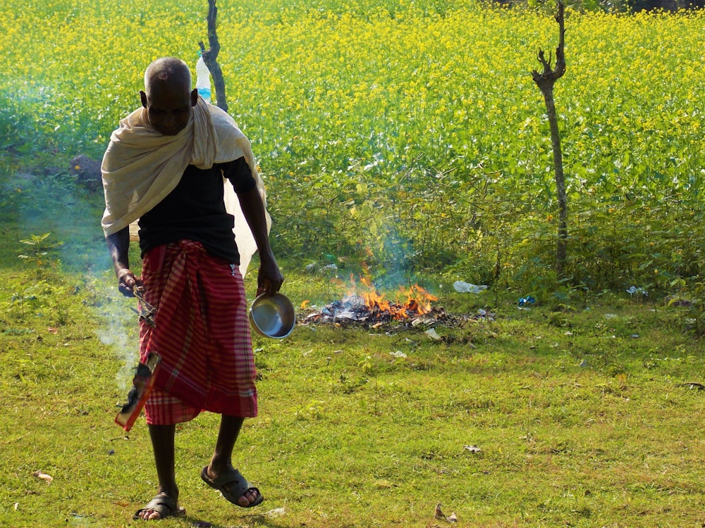 a man standing in a field holding a pot