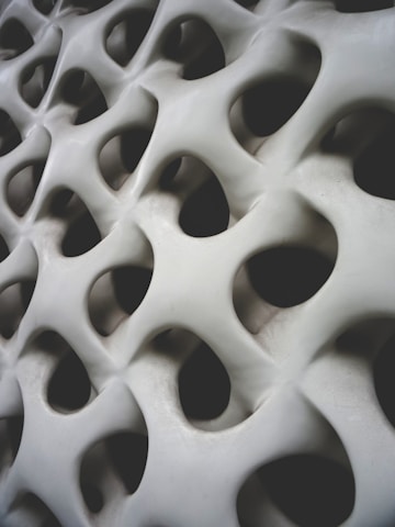 Organic, three-dimensional surface with smooth, flowing curves and multiple holes resembling a honeycomb or biological structure.