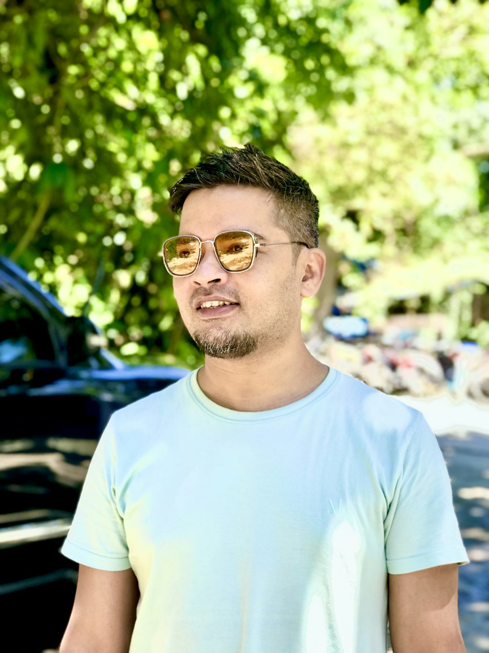 a man wearing sunglasses standing in front of a car
