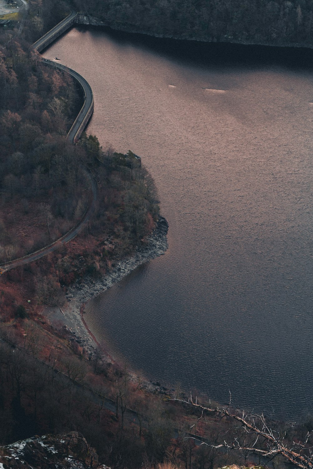 an aerial view of a winding road next to a body of water