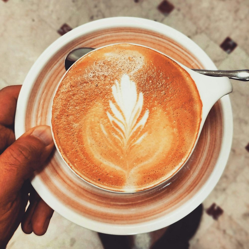 a person holding a cup of coffee with a spoon in it