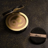 Hands holding a compact powder case with the Skin with Talia logo.