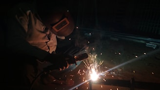 a man welding a piece of metal in the dark