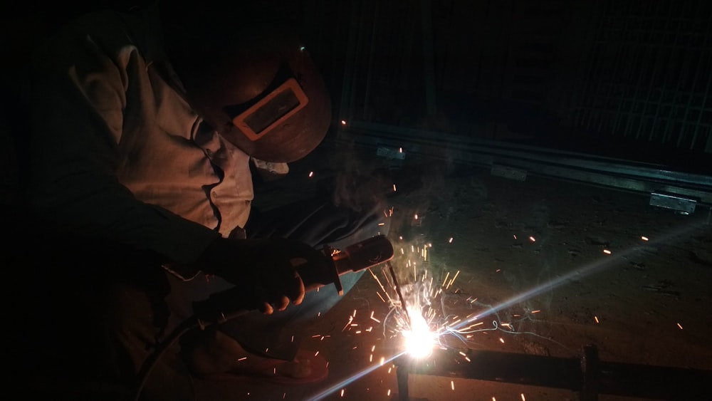 a man welding a piece of metal in the dark