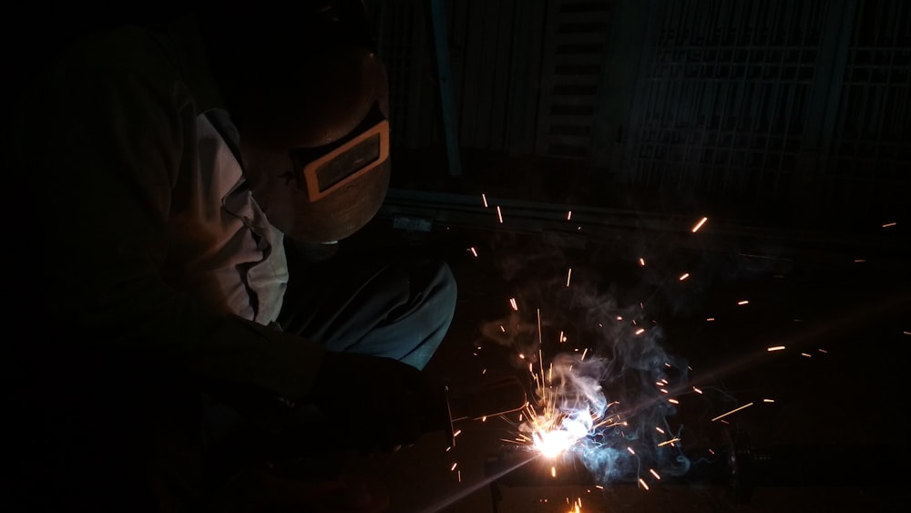 a man working on a piece of metal in the dark