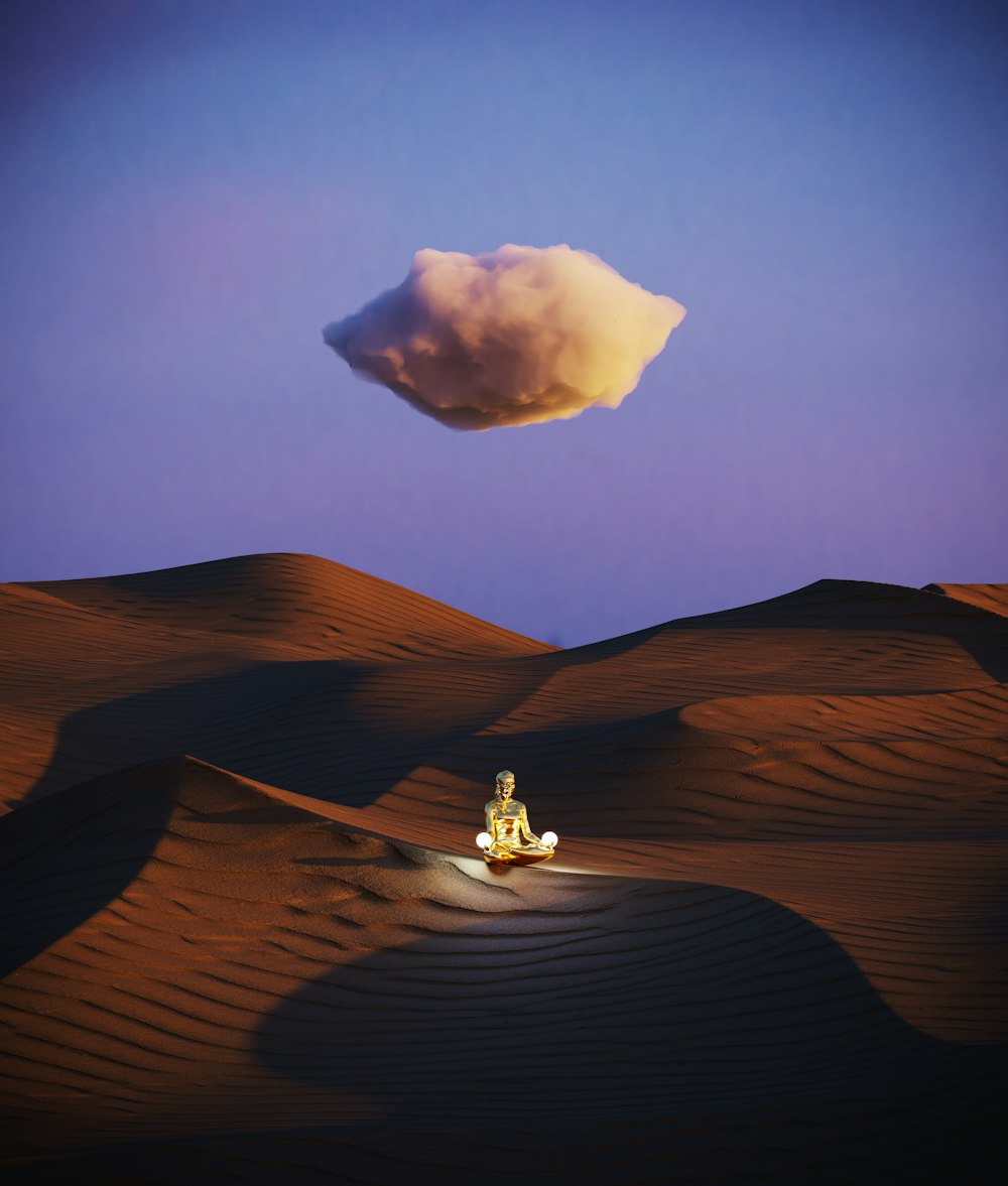 a person sitting in the middle of a desert under a cloud
