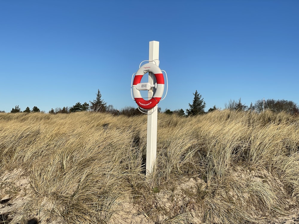 a red and white sign sitting in the middle of a field