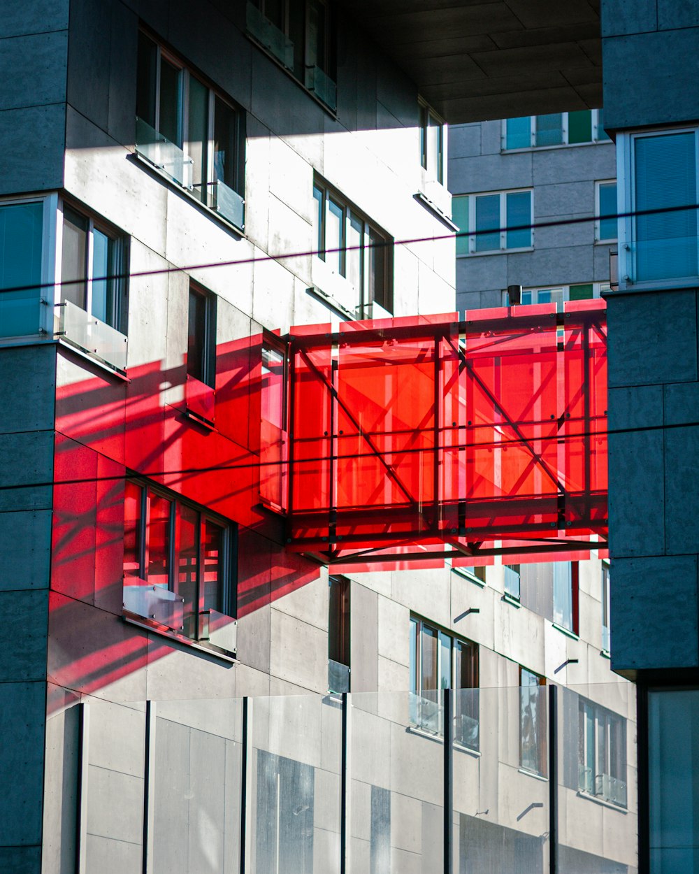 a red bridge over a city street next to a tall building