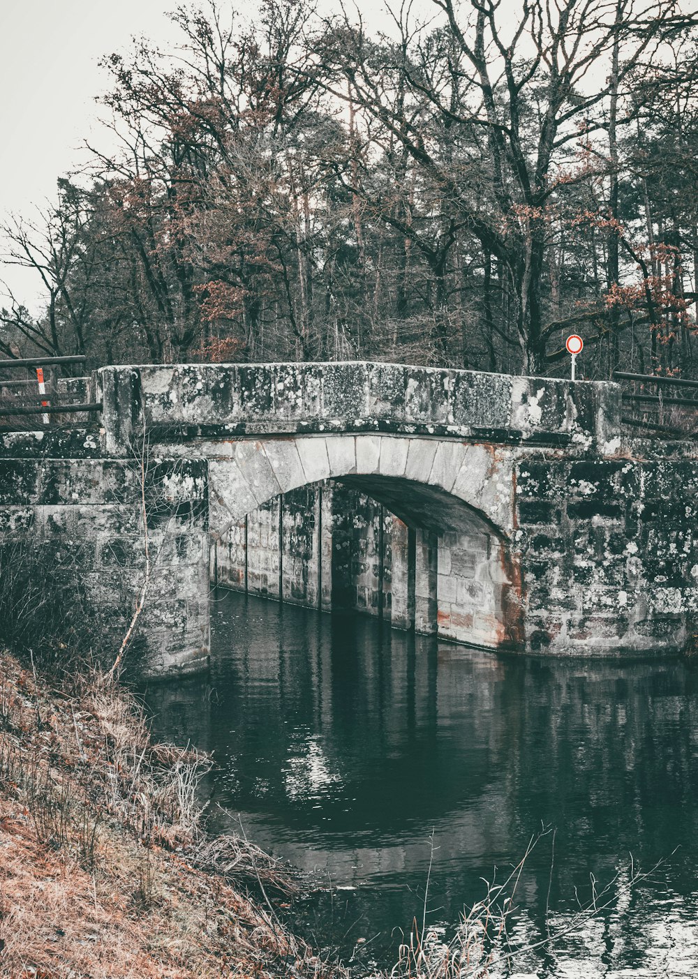 a stone bridge over a river in a wooded area