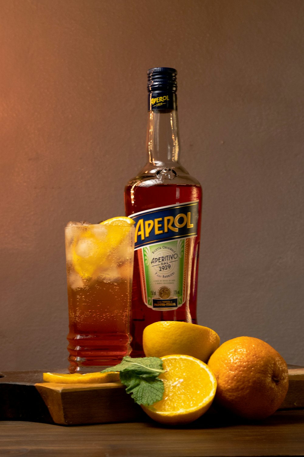 a bottle of aperol next to some lemons and a glass