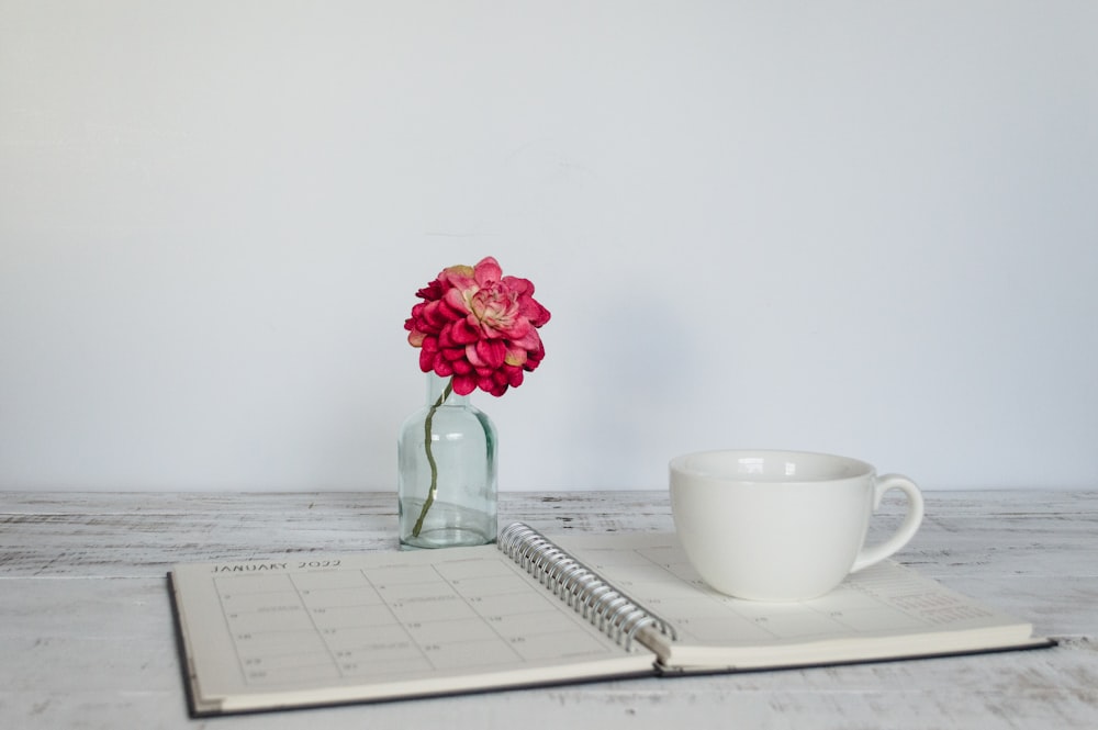 a cup of coffee and a flower in a vase