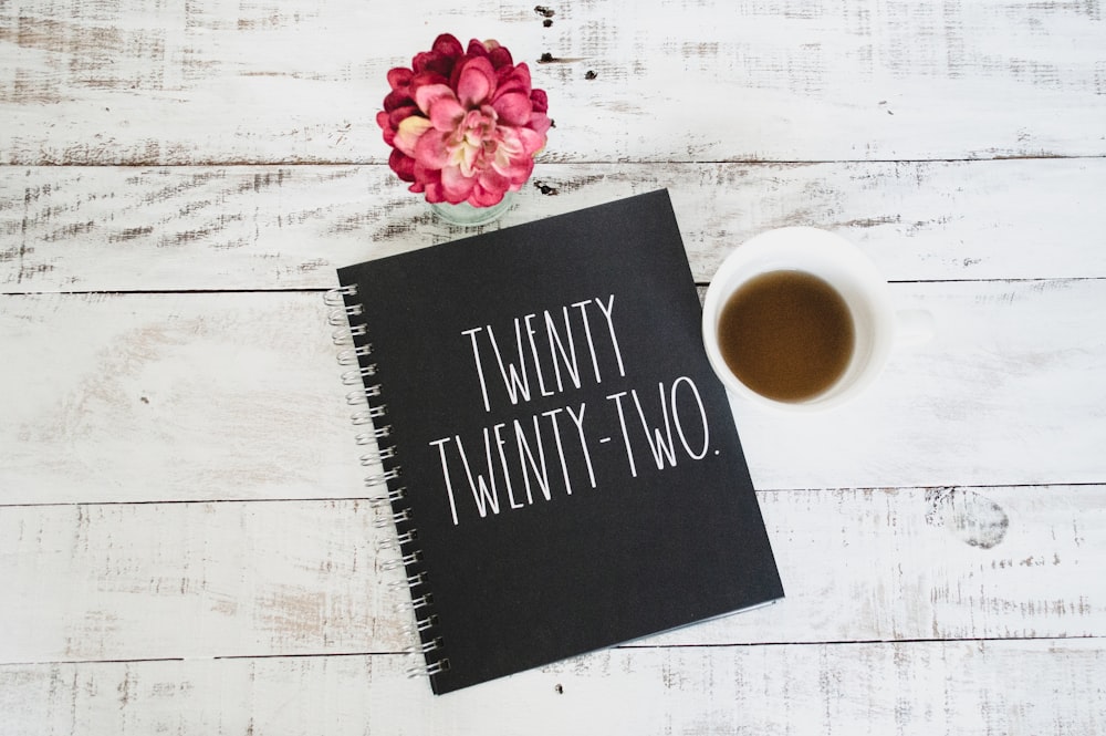 a notebook with the words twenty twenty two next to a cup of coffee