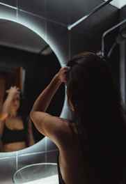 a woman standing in front of a bathroom mirror