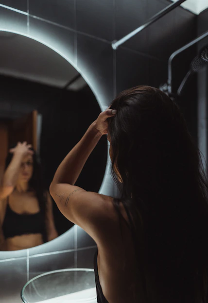 a woman standing in front of a bathroom mirror